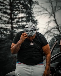 a man standing next to a car with a hat on his head